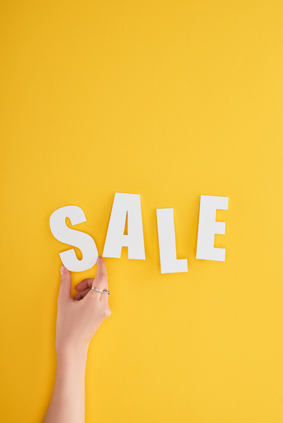cropped view of woman holding sale lettering on yellow background - Foto, imagen