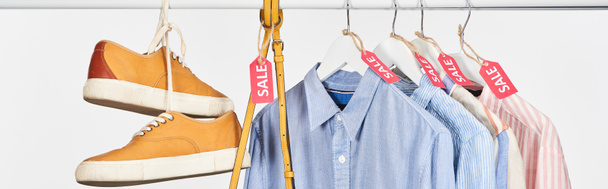 baskets, sac et chemises élégantes suspendues avec des étiquettes de vente isolées sur blanc, vue panoramique
 - Photo, image