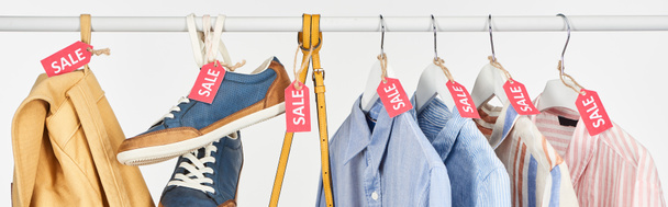 sneakers, accessories and elegant shirts hanging with sale labels isolated on white, panoramic shot - Photo, Image