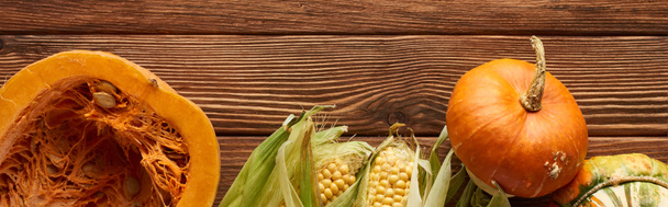 plano panorámico de maíz dulce crudo, entero y la mitad de la calabaza en la superficie de madera marrón
 - Foto, Imagen