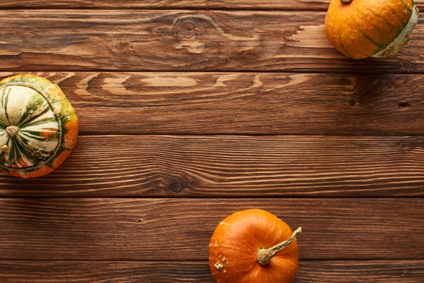 top view of raw small pumpkins on brown wooden surface with copy space - Foto, Imagem