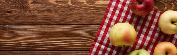 panoramic shot of checkered tablecloth with fresh apples on wooden surface - Photo, Image