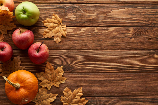 vista dall'alto di zucca piccola e mele su superficie di legno marrone con foglie di autunno asciugate
 - Foto, immagini