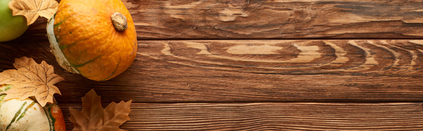 панорамный снимок маленьких тыкв на деревянной поверхности с сушеными осенними листьями
 - Фото, изображение