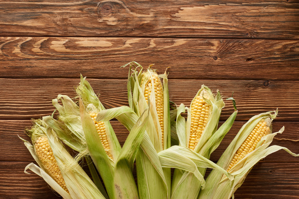 top view of uncooked sweet corn on wooden surface with copy space - Foto, Imagen