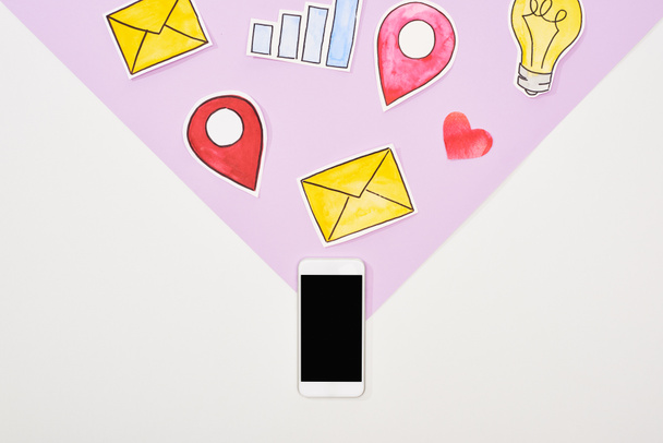 Ansicht des Smartphones von oben mit leerem Bildschirm und papiergeschnittenen sozialen Netzwerk-Symbolen auf violett-weißem Hintergrund - Foto, Bild