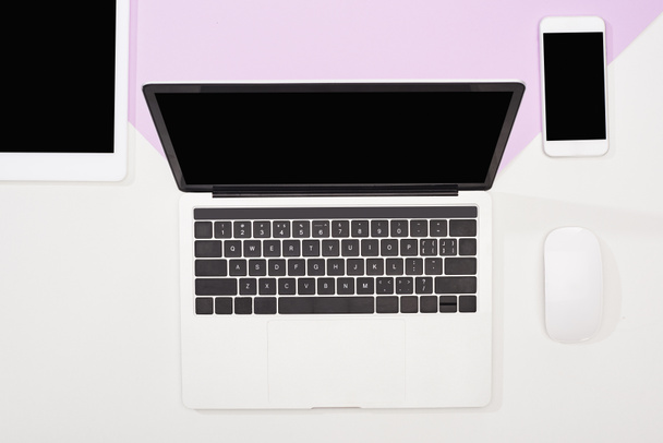flat lay with laptop, digital tablet, smartphone with blank screen and computer mouse on violet and white background - Photo, Image