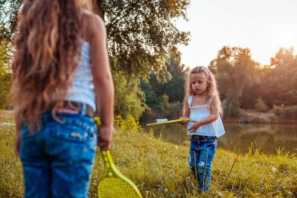 Badminton. Little girl playing badminton with sister in summer park. Kids having fun outdoors. Outdoor games - Fotoğraf, Görsel