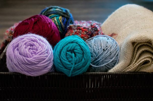 Hilos coloridos madejas para tejer o ganchillo con manta blanca dentro de la cesta de mimbre
  - Foto, Imagen