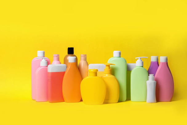 Different bottles of shampoo on yellow background. Natural cosmetic products - Foto, Imagen
