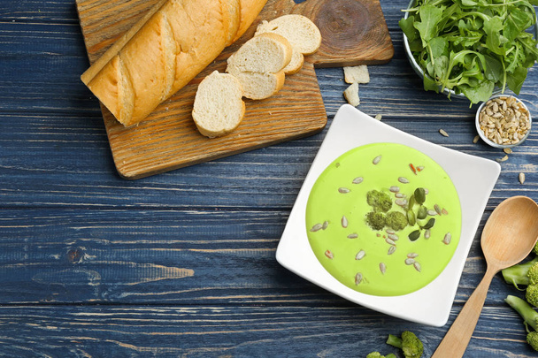 Flat lay composition with bowl of broccoli cream soup on blue wooden table. Space for text - Φωτογραφία, εικόνα
