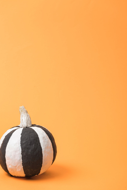 striped painted black and white pumpkin on orange background - Фото, изображение