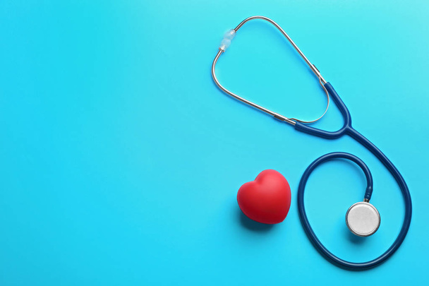 Stethoscope and red heart on blue background, flat lay with space for text - Foto, Imagen