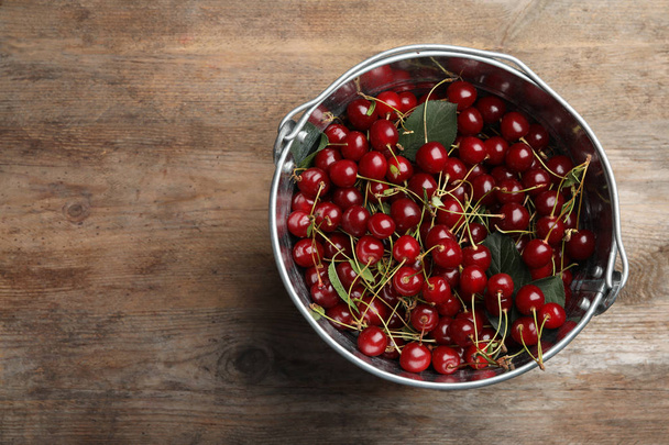 Bucket of delicious cherries on wooden table, top view. Space for text - Фото, зображення