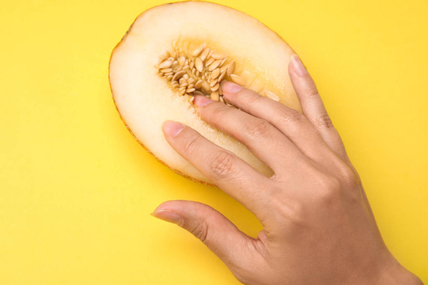 Young woman touching half of melon on yellow background, above view. Sex concept - Foto, Bild