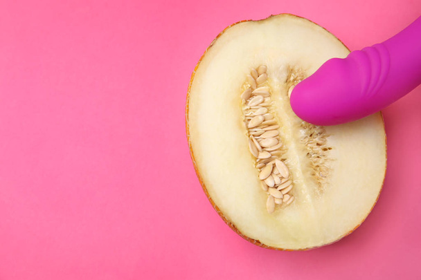 Half of melon and purple vibrator on pink background, flat lay with space for text. Sex concept - Foto, imagen