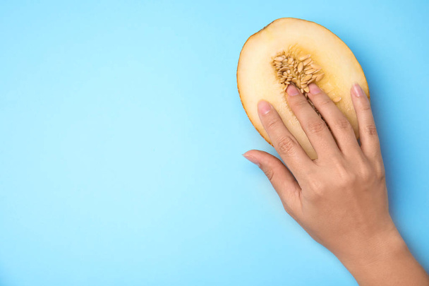 Young woman touching half of melon on blue background, top view with space for text. Sex concept - 写真・画像