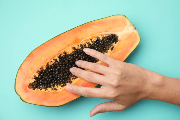 Young woman touching half of papaya on turquoise background, top view. Sex concept - Φωτογραφία, εικόνα