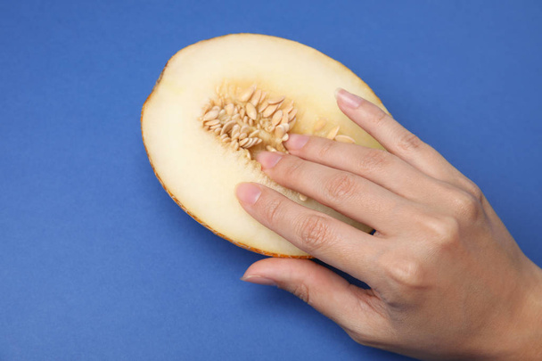 Young woman touching half of melon on blue background, above view. Sex concept - Valokuva, kuva