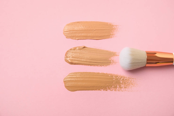 Samples of different foundation shades and makeup brush on pink background, above view - Fotografie, Obrázek