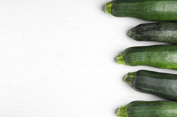Fresh ripe green zucchinis on white wooden table, flat lay. Space for text - Foto, imagen