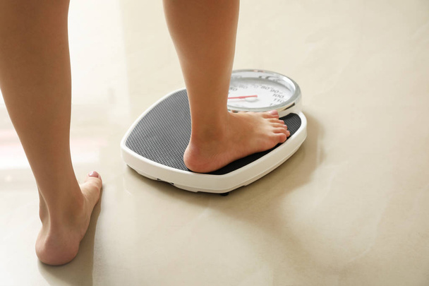 Woman stepping on floor scales indoors. Overweight problem - Foto, immagini