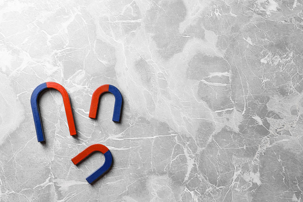 Red and blue horseshoe magnets on grey marble background, flat lay. Space for text - 写真・画像
