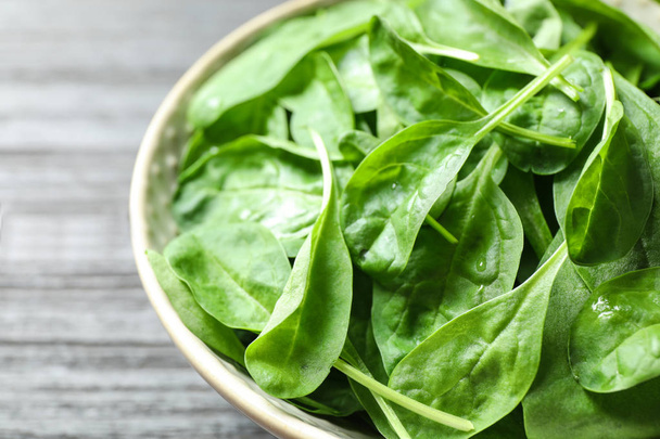 Bowl of fresh green healthy spinach on dark wooden table, closeup - Foto, Imagen