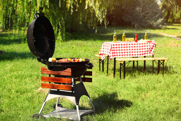 Modern barbecue grill with tasty food in park - 写真・画像
