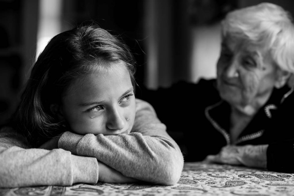 Маленька дівчинка втішається своєю бабусею. Чорно-біле фото
. - Фото, зображення