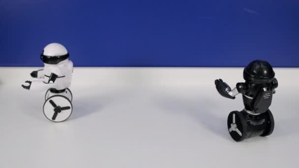pequeños robots de juguete en blanco y negro conducen sobre la superficie de la mesa
 - Metraje, vídeo