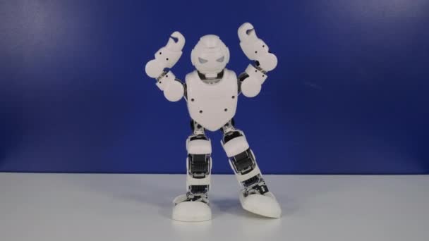 маленький человекоподобный робот делает танцевальные движения на стенде
 - Кадры, видео