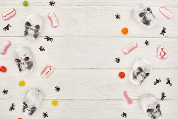 vista superior de bombones, dientes de goma, cráneos y arañas en la mesa blanca, regalo de Halloween
 - Foto, Imagen