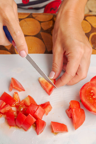 Dicing fresh ripe tomatoes on a white cutting Board - Fotó, kép
