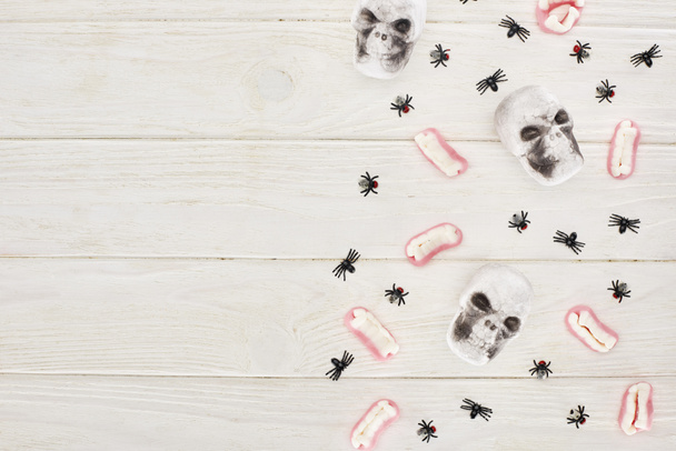 pohled na gumové zuby, lebky a pavouky na bílém stole, dárek na Halloween - Fotografie, Obrázek