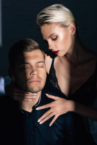 attractive woman in black underwear hugging handsome man in shirt with closed eyes  - Photo, Image