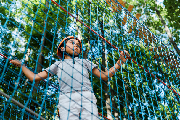low angle view of adorable african american boy in high rope trail  - Fotografie, Obrázek