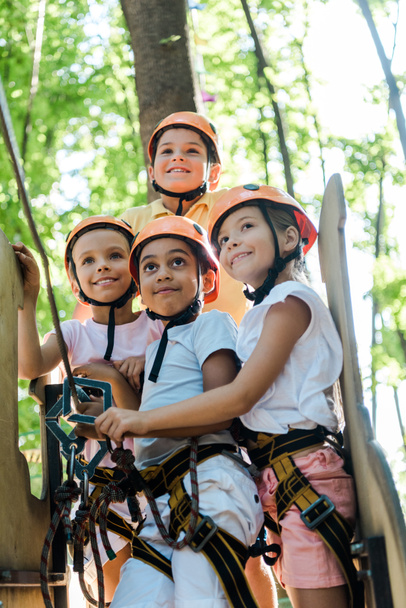 positive multicultural kids looking up in adventure park outside  - Photo, Image
