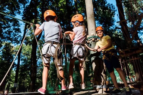 multicultural boys in helmets near friend on high rope trail  - Photo, Image