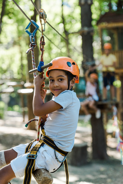 selective focus of adorable african american kid in orange helmet in adventure park  - Photo, Image