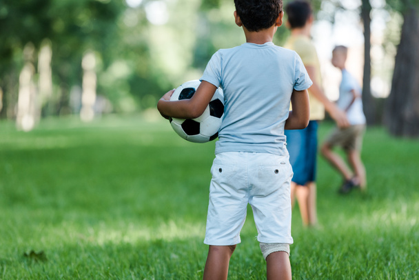 back view of african american child standing with football near boys  - Foto, Imagen
