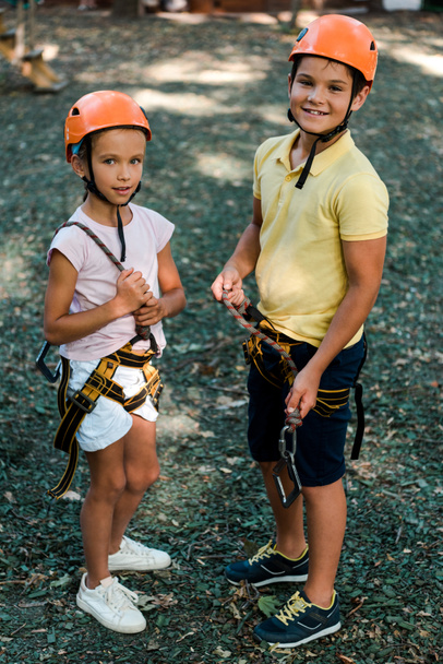 счастливые дети в шлемах стоят и смотрят в камеру снаружи
  - Фото, изображение