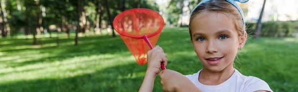 panoramic shot of happy kid holding butterfly net outside  - Foto, imagen