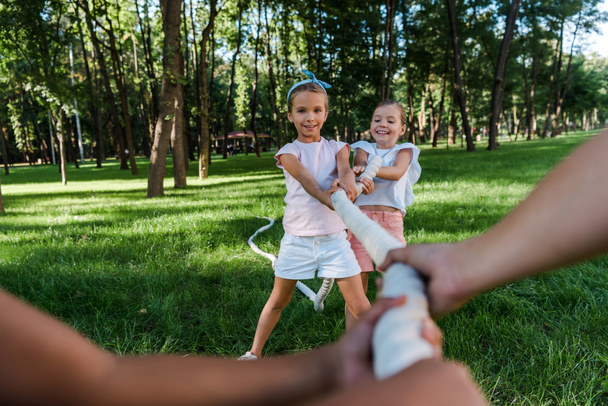 selective focus of cheerful multicultural children competing in tug of war outside  - Фото, зображення