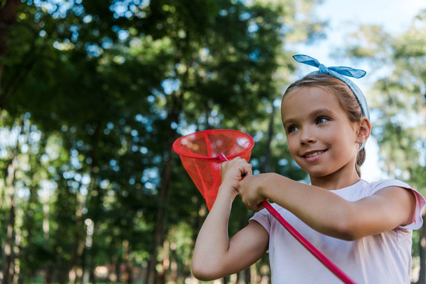Positives Kind hält Schmetterlingsnetz im grünen Park  - Foto, Bild