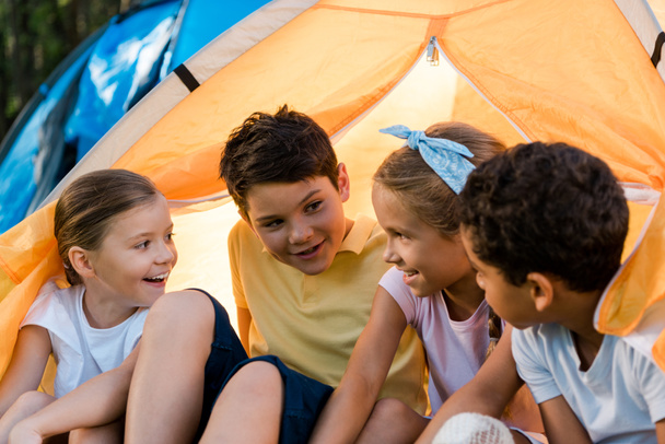 heureux enfants multiculturels assis dans le camp jaune
  - Photo, image
