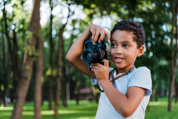 lindo africano americano chico holding digital cámara en parque
  - Foto, Imagen