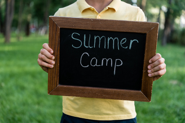 cropped view of boy holding chalk board with summer camp letters  - Photo, Image