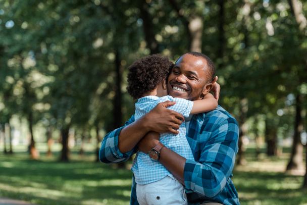 heureux père afro-américain avec les yeux fermés étreignant fils bouclé
  - Photo, image
