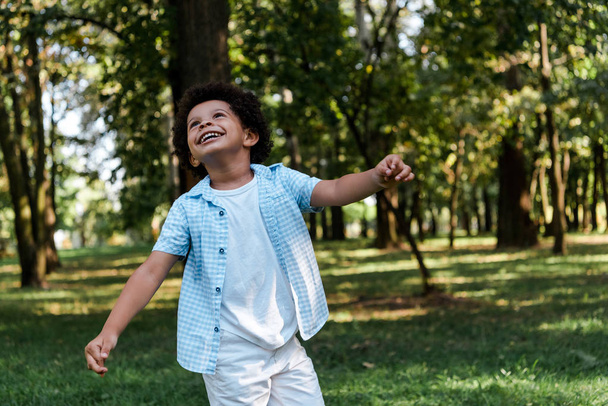 feliz afroamericano chico mirando hacia arriba en parque
  - Foto, imagen